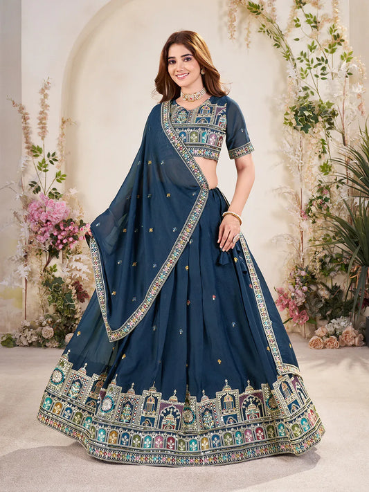 Woman wearing a traditional blue embroidered saree with a floral decorated background Glanzavi
