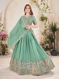 Woman wearing a light blue embroidered Lehenga with a matching blouse in a decorated indoor setting Glanzavi
