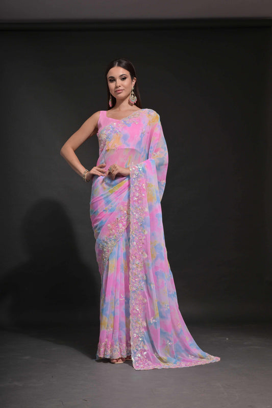 A woman modeling a pastel pink tie-dye saree with multicolor sequin floral embroidery, standing against a dark background Glanzavi