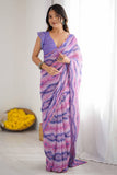 Woman wearing a purple and pink saree with a white curtain and yellow flowers in the background Glanzavi