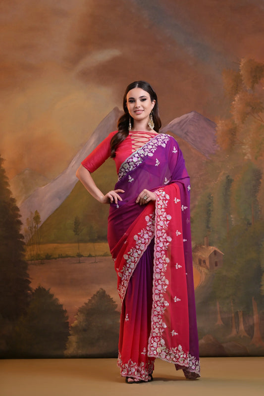 Woman in a purple and red saree standing in front of a scenic backdrop Glanzavi