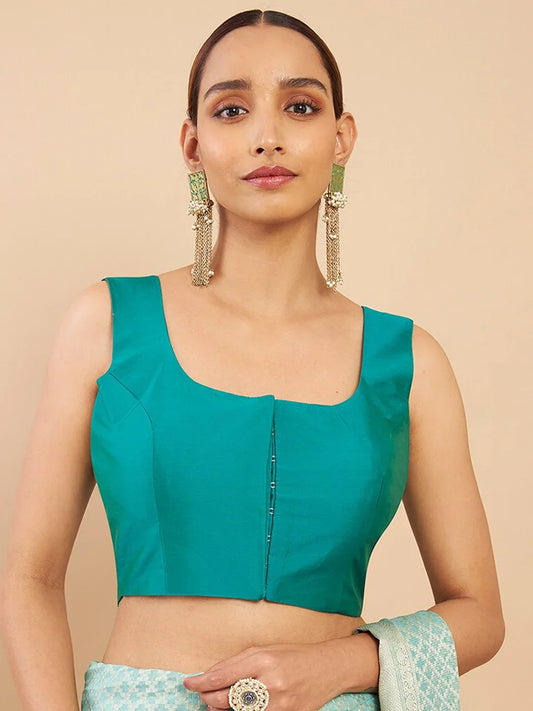 Woman wearing a teal blouse with a beige background Glanzavi