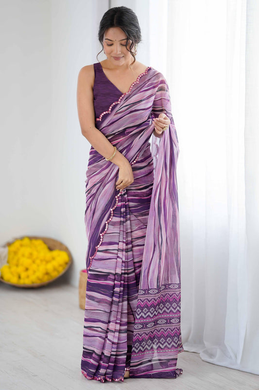 Woman wearing a purple and white saree with a white curtain and yellow flowers in the background Glanzavi