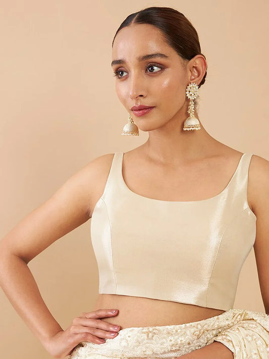 Woman wearing a beige sleeveless top with a plain background Glanzavi