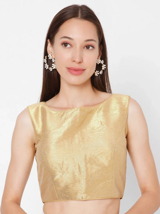 Woman wearing a gold blouse with a plain background Glanzavi