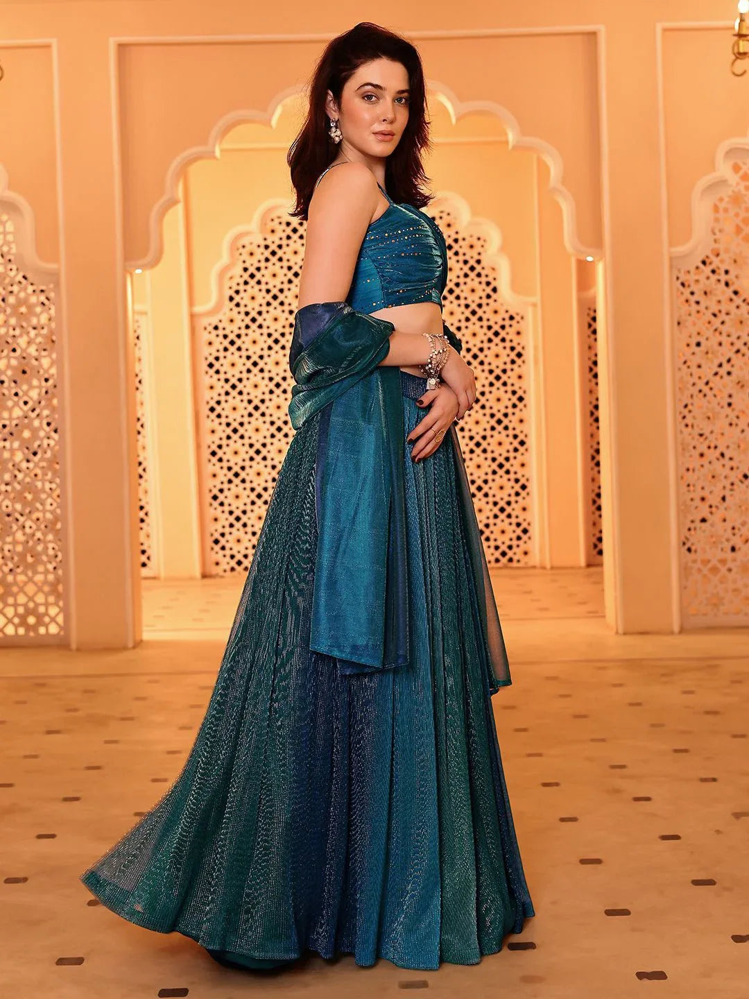 Woman in a blue traditional outfit standing in a decorated room Glanzavi