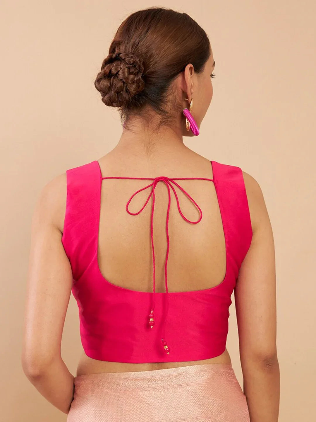 Woman wearing a pink blouse with a back design on a beige background Glanzavi