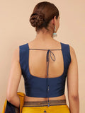 Woman wearing a blue blouse with an open back design on a beige background Glanzavi