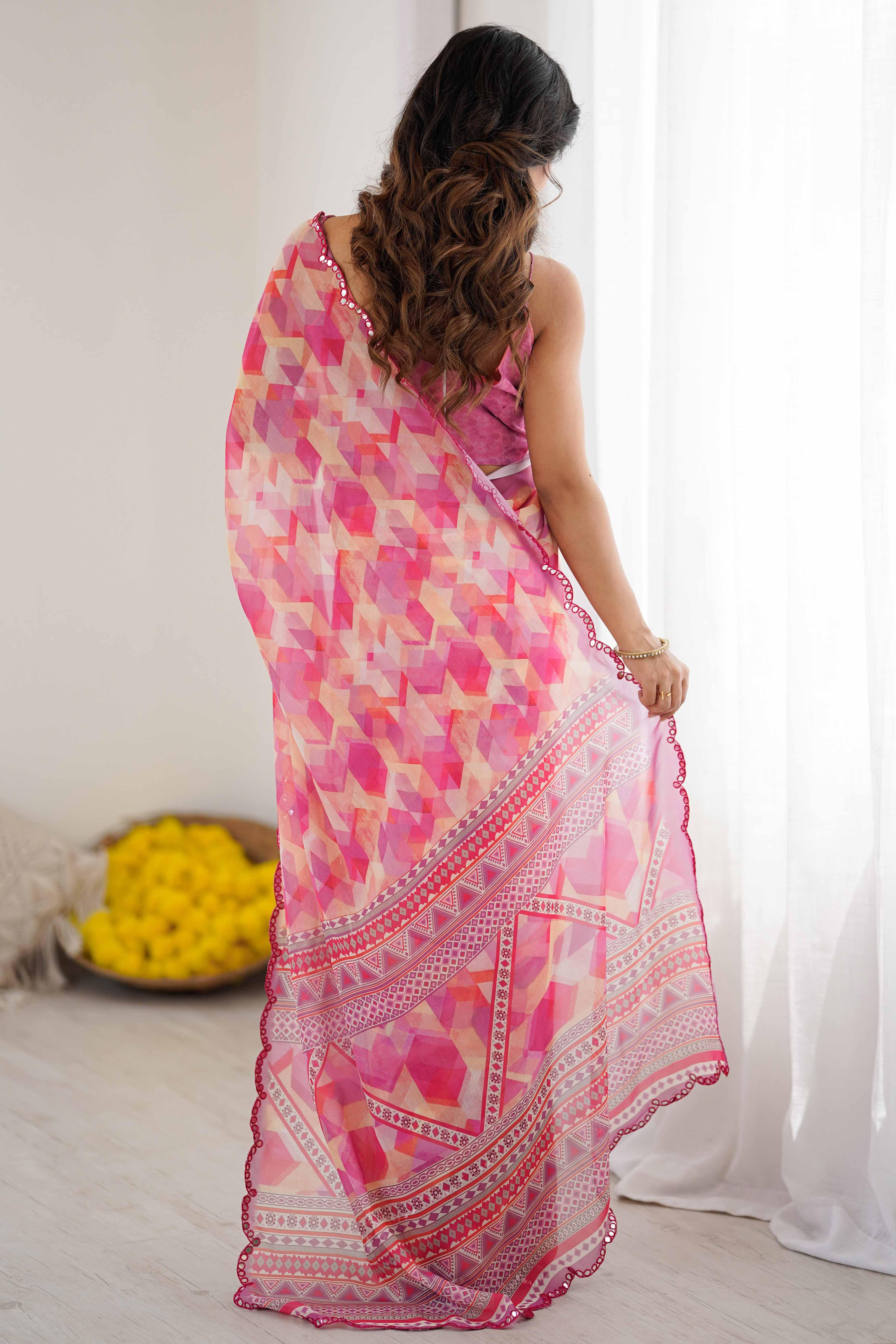 Woman wearing a pink and yellow patterned saree in a room with white curtains and a bowl of flowers Glanzavi.