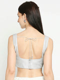 Woman wearing a light gray sleeveless top with a back design on a white background Glanzavi
