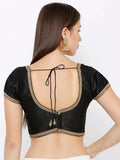 Black blouse with gold detailing on a plain background Glanzavi