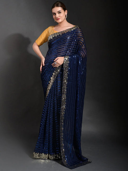 Woman wearing a blue saree with gold blouse against a dark background Glanzavi
