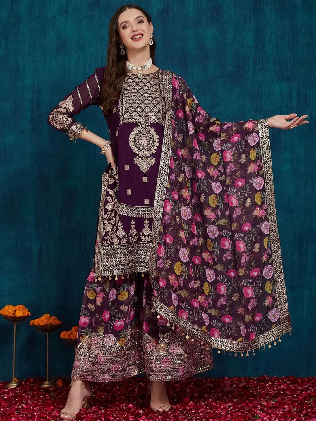 Woman in a traditional outfit with a floral dupatta against a blue background Glanzavi