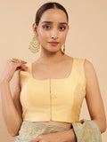 Woman wearing a yellow blouse with gold jewelry against a beige background Glanzavi