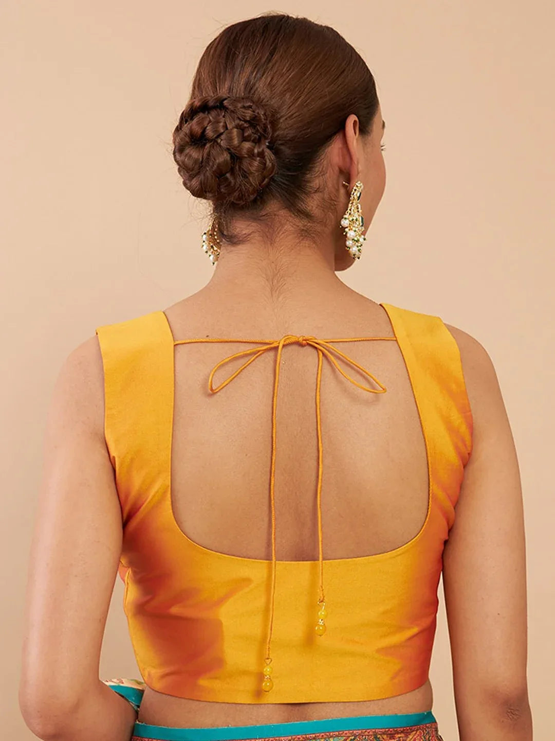 Woman wearing a yellow blouse with a sheer back design on a beige background Glanzavi
