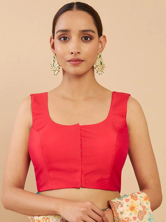 Woman wearing a red blouse with floral earrings against a beige background Glanzavi