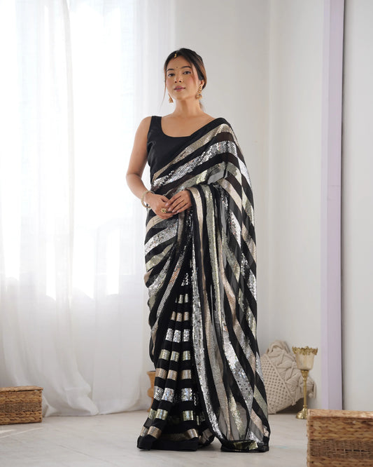 Woman wearing a black and silver saree against a white curtain background Glanzavi