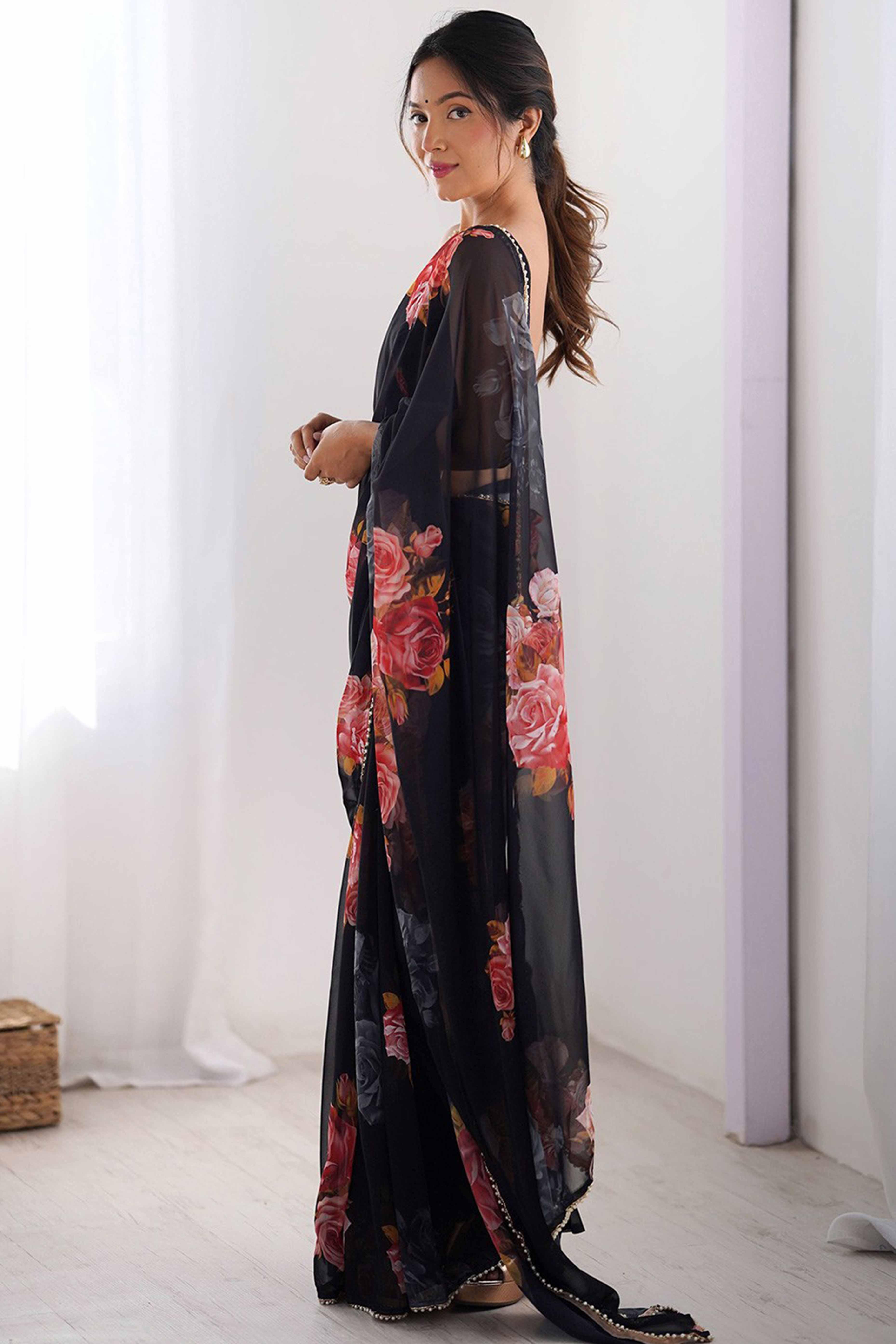 Woman wearing a black floral dress standing in a room with white curtains Glanzavi.
