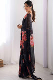 Woman wearing a black floral dress standing in a room with white curtains Glanzavi.