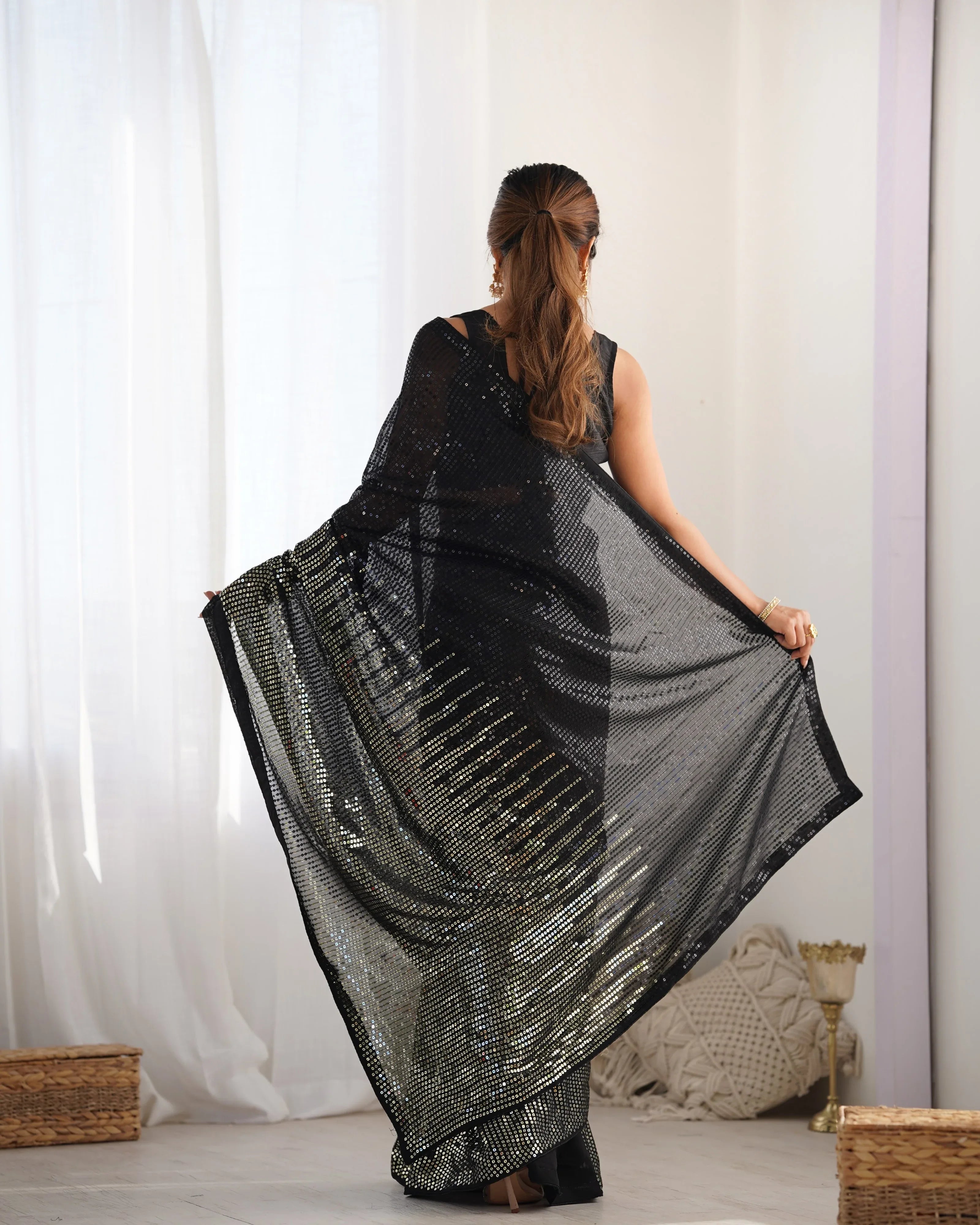 Woman wearing a black and gray patterned dress against a white curtain background Glanzavi