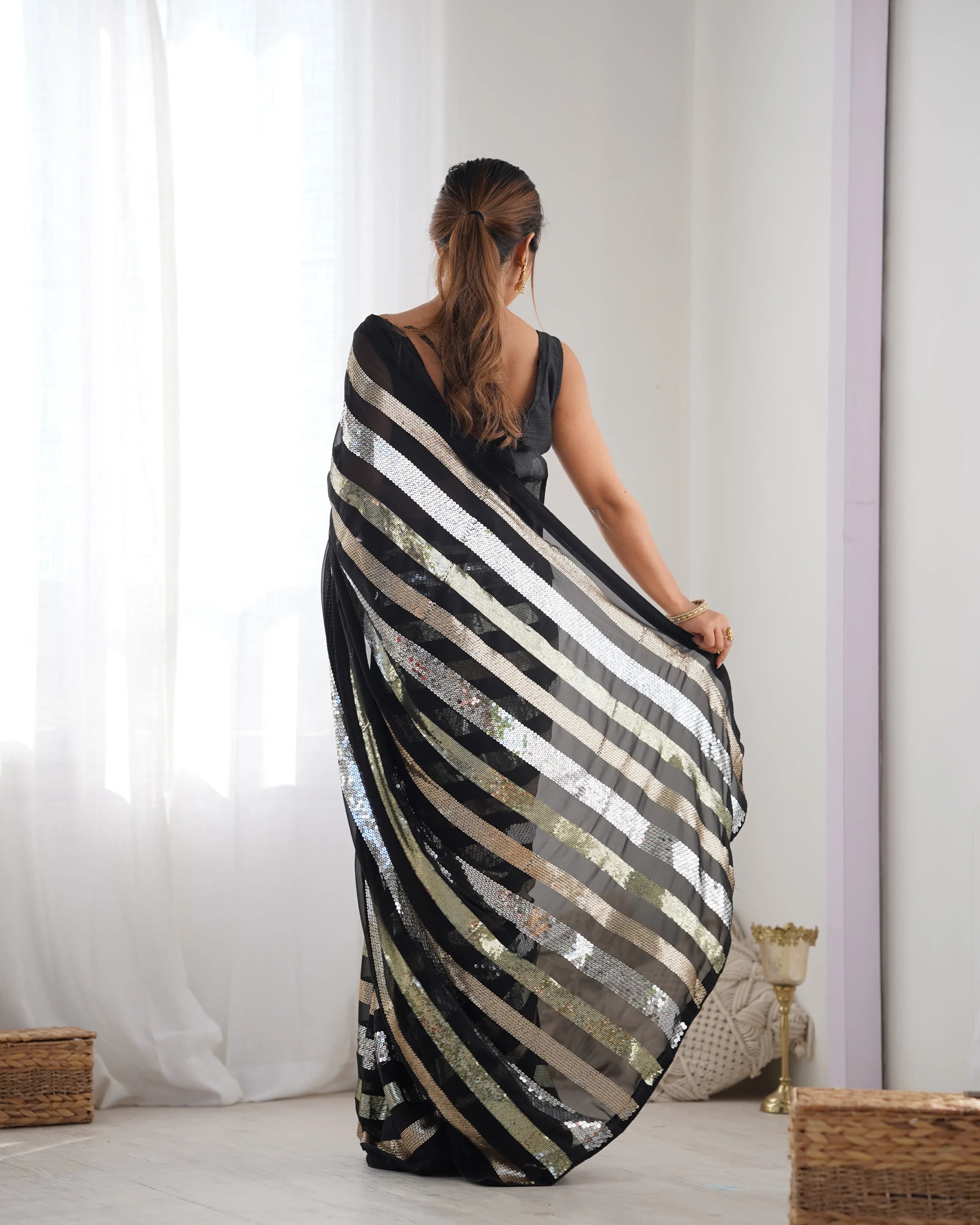Woman holding a black and white striped fabric against a white curtain background Glanzavi