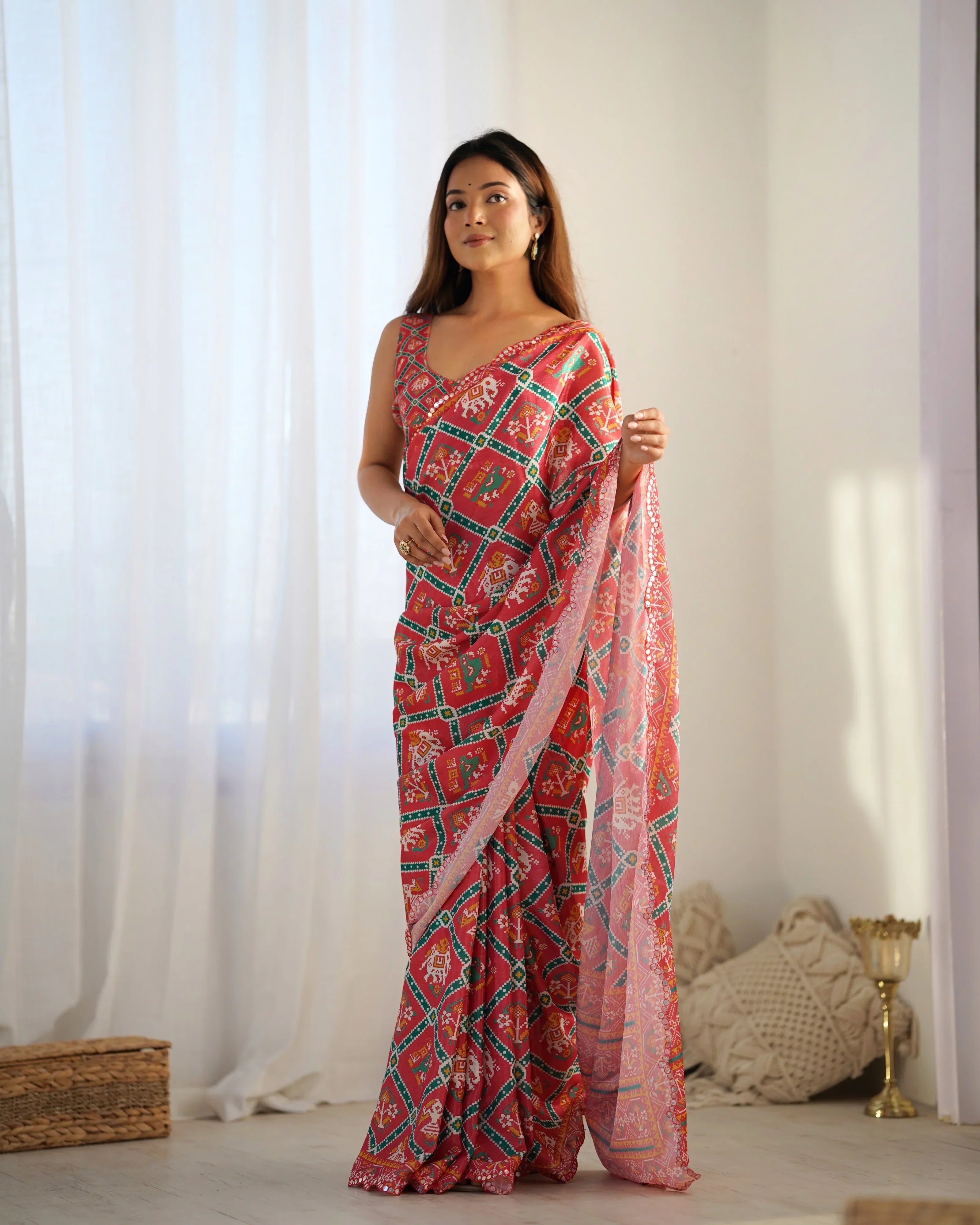 Woman wearing a red and green patterned saree with a white background Glanzavi
