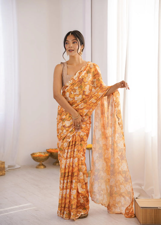 Woman wearing a Orange saree in a room with white curtains and a small table Glanzavi.