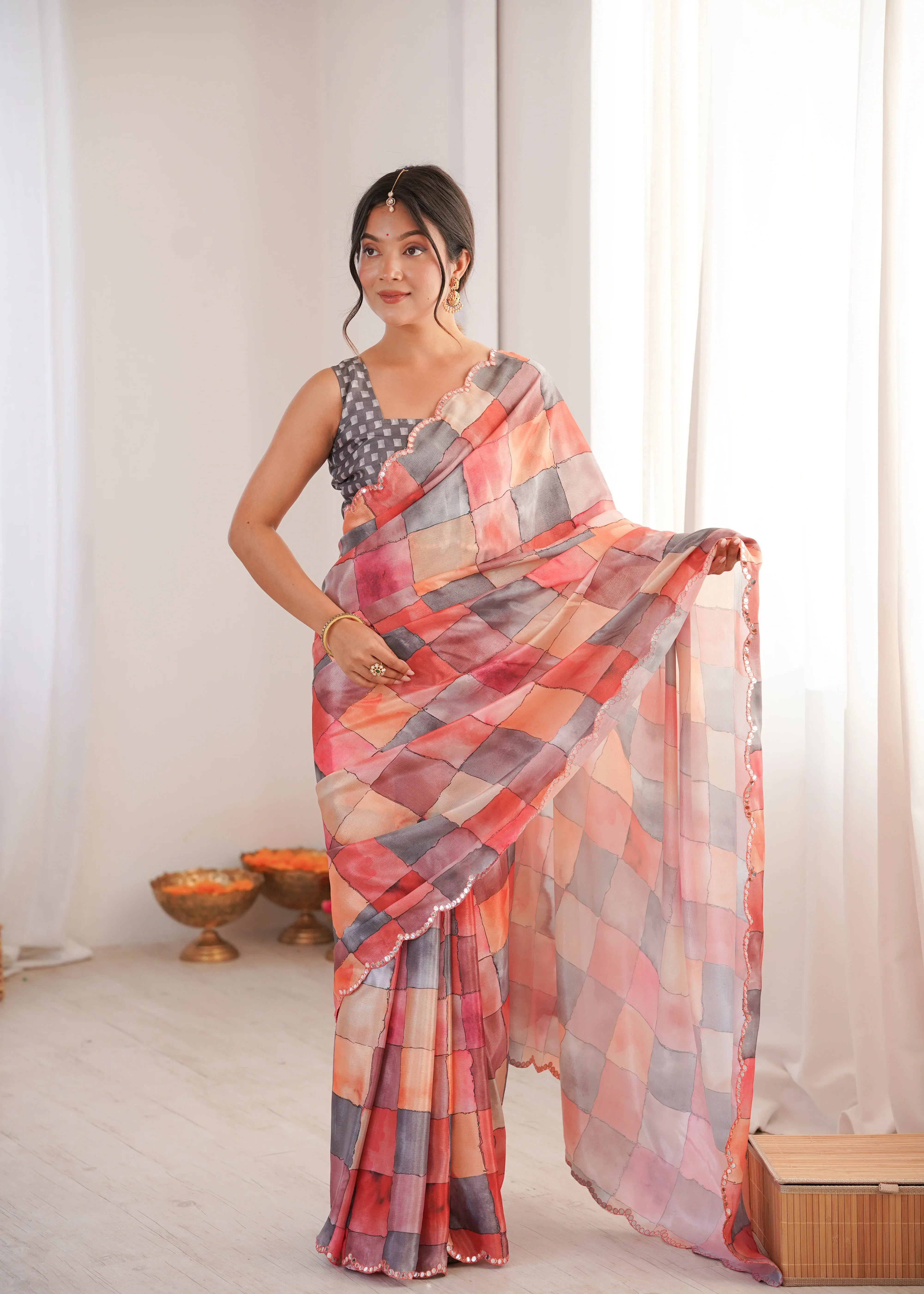 Woman wearing a colorful saree in a room with white curtains and a small table Glanzavi.