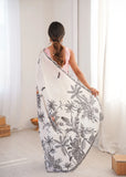 Woman holding a white scarf with black floral patterns in a bright room Glanzavi.