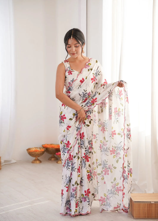 Woman wearing a floral dress holding a matching scarf in a bright room Glanzavi.