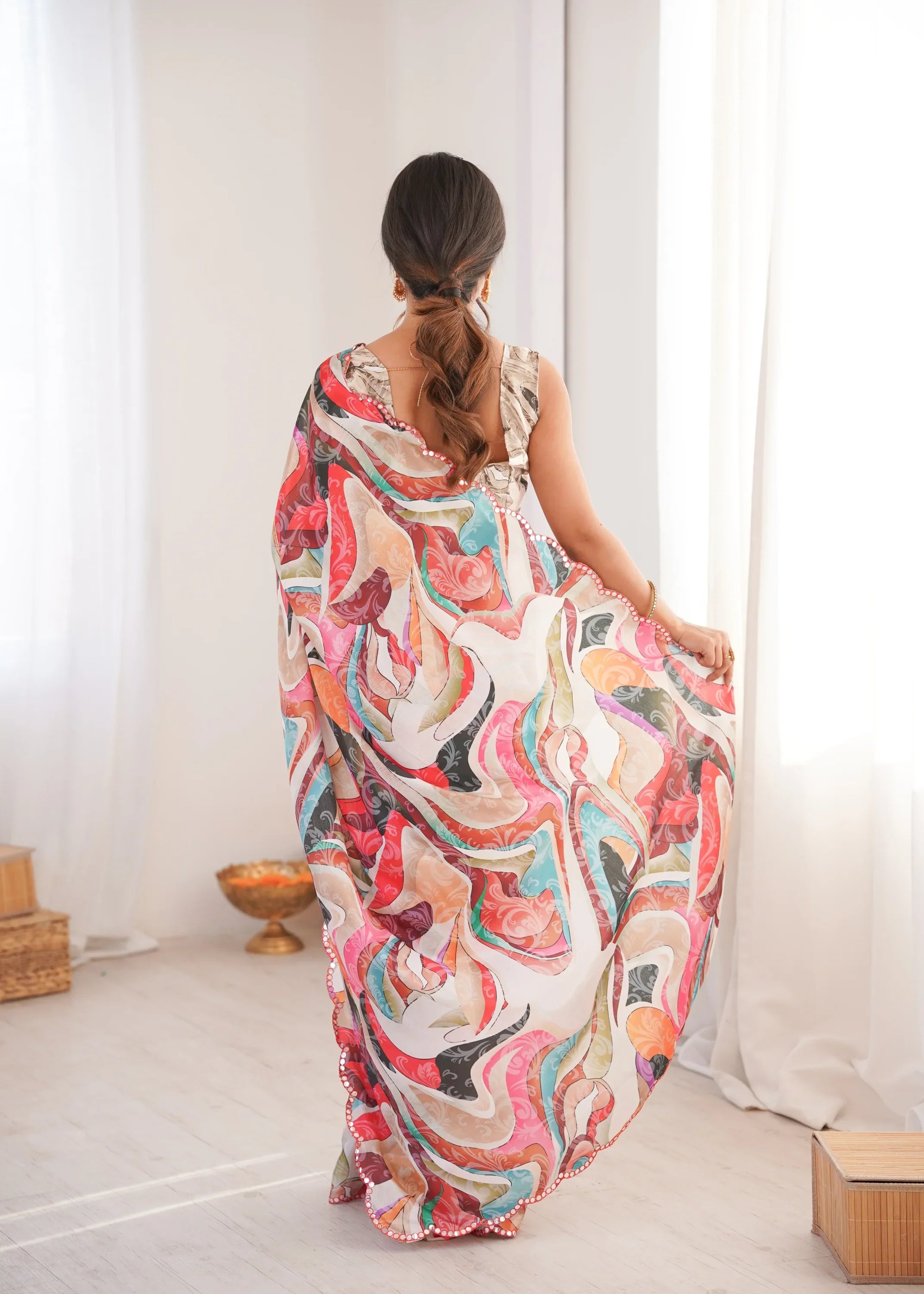 Woman wearing a colorful floral dress in a bright room with white curtains Glanzavi.