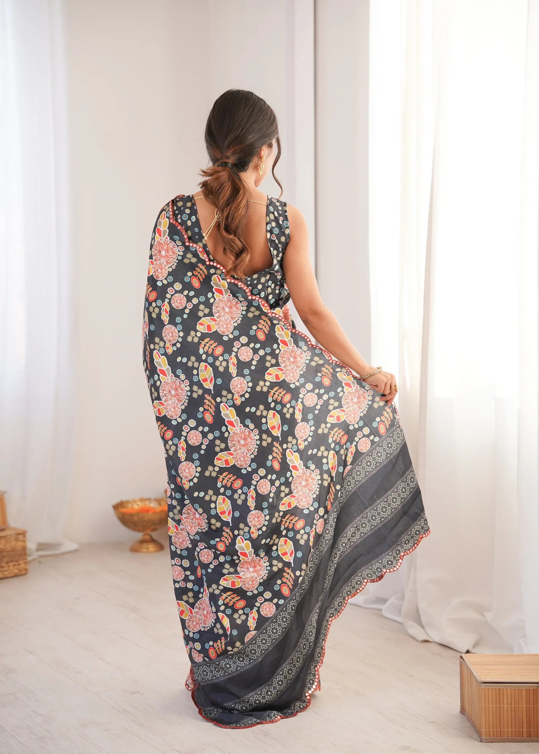 Woman holding a floral saree in a minimal indoor setting Glanzavi