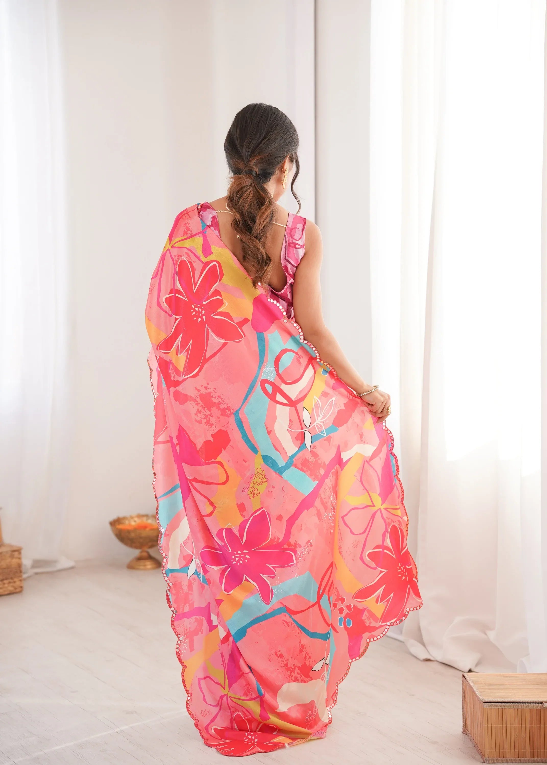 Woman wearing a colorful floral dress in a minimal indoor setting Glanzavi