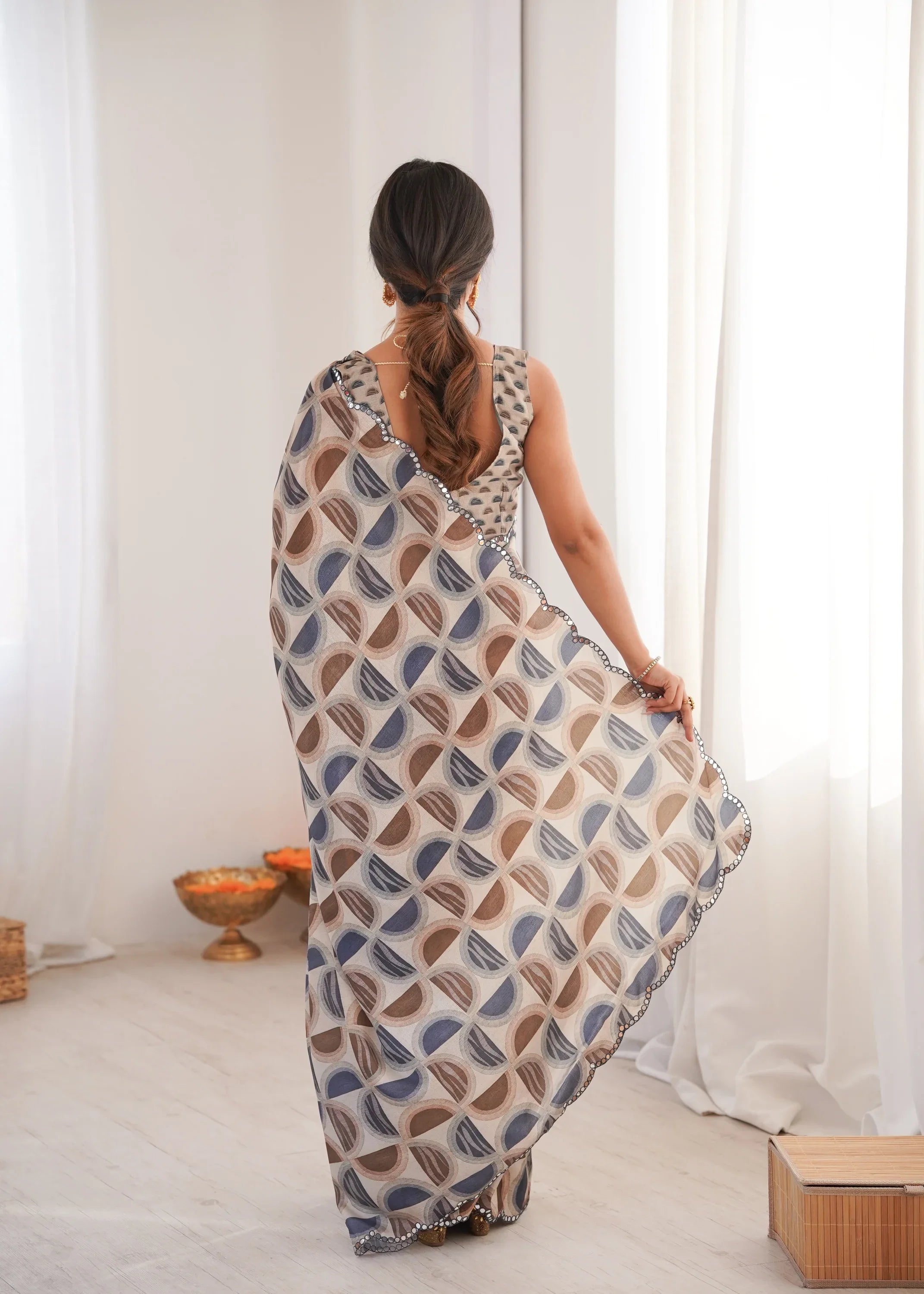 Woman wearing a patterned saree in a minimalistic room Glanzavi.