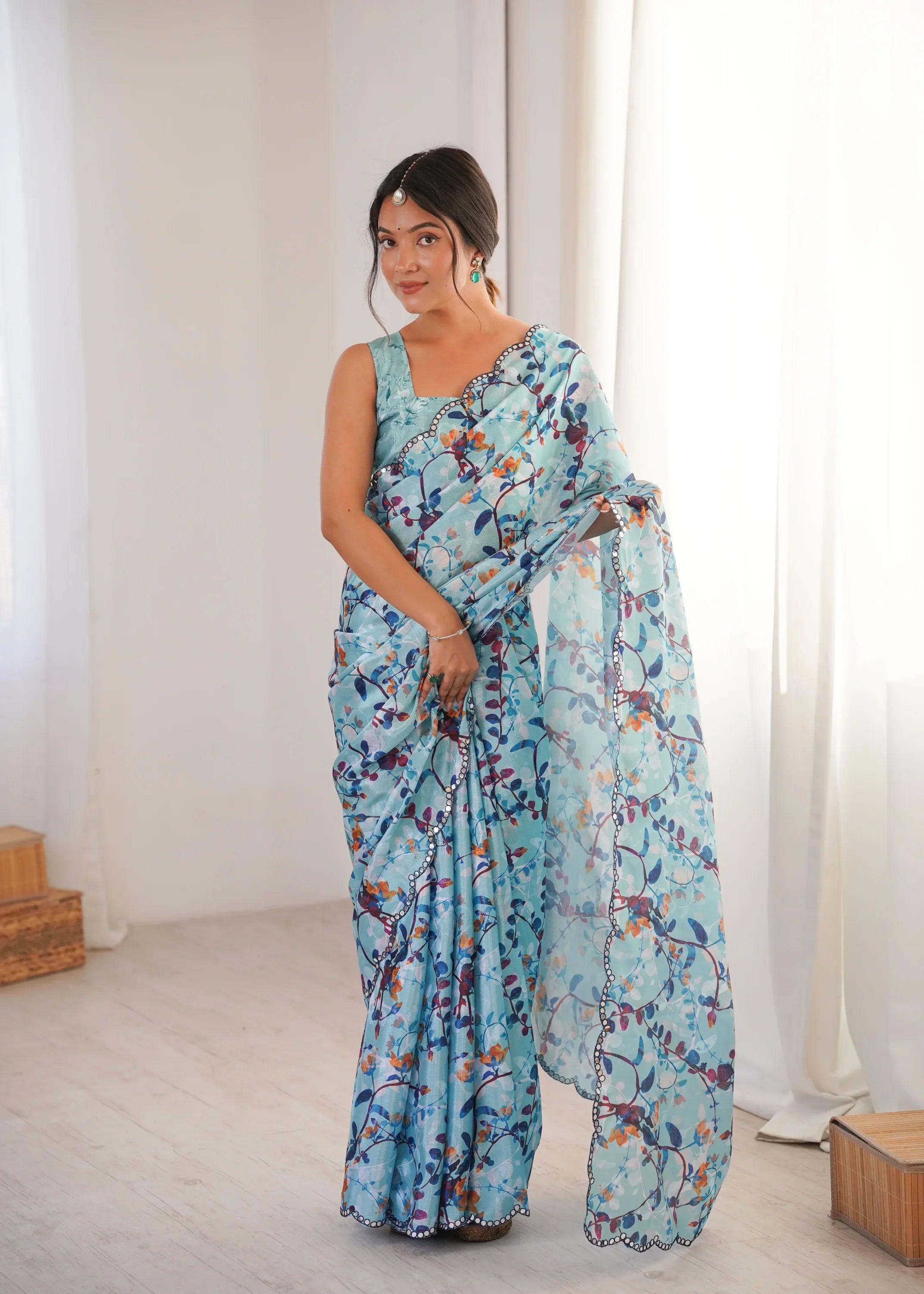 Woman wearing a light blue floral saree in a minimalistic setting Glanzavi