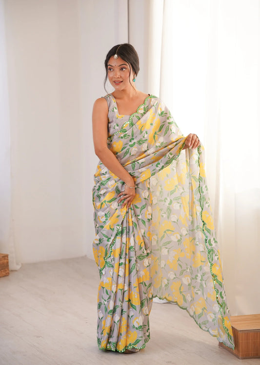 Woman wearing a floral saree with a yellow and green pattern in a minimal indoor setting. || Glanzavi