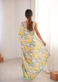 Woman wearing a floral dress with yellow flowers in a minimal indoor setting Glanzavi