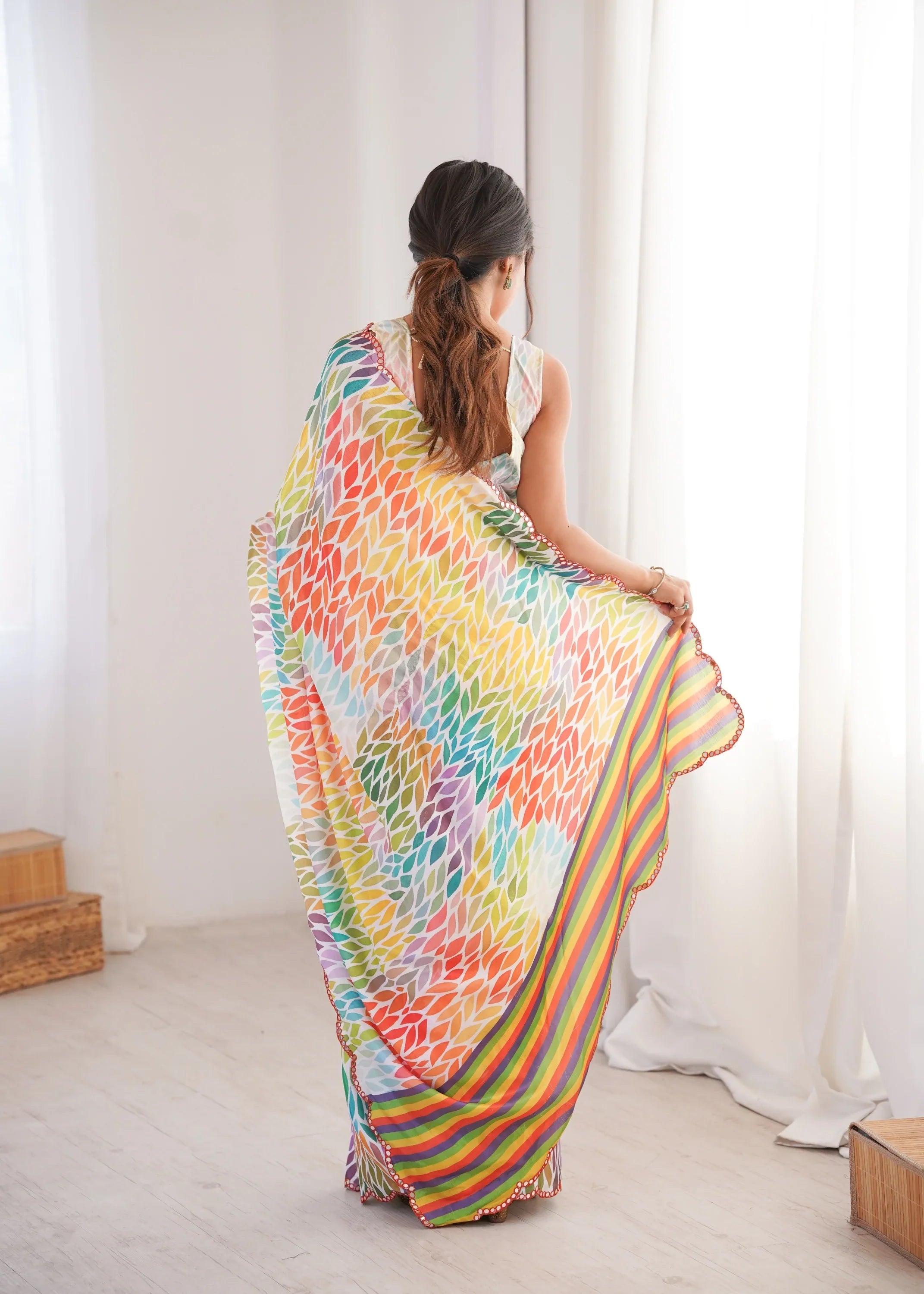 Woman wearing a colorful saree in a bright room with white curtains Glanzavi.