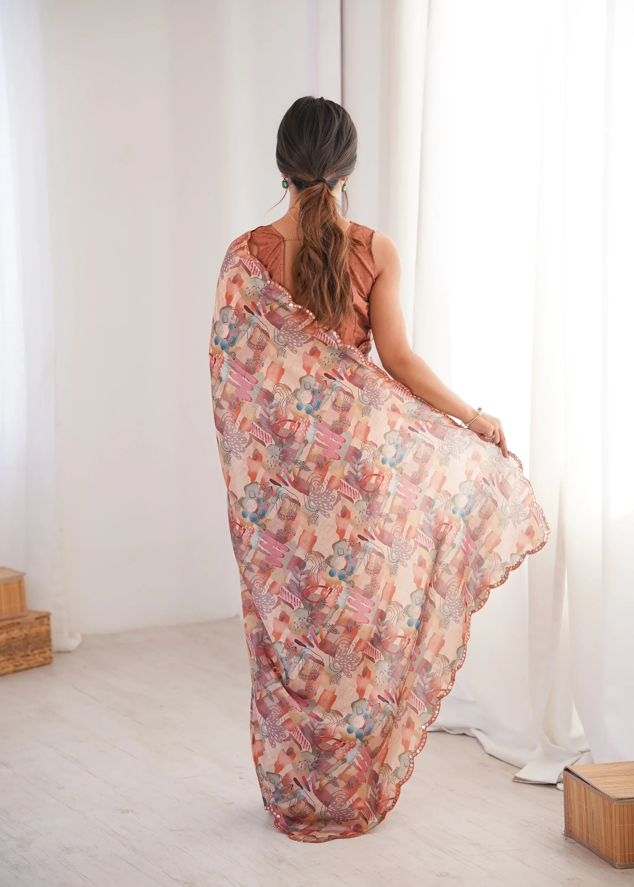 Woman holding a floral saree in a minimal indoor setting Glanzavi