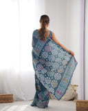 Woman wearing a blue patterned saree in a minimalistic room Glanzavi