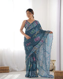 Woman wearing a blue patterned saree against a white background Glanzavi