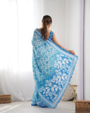 Woman wearing a blue and white floral saree in a minimal indoor setting Glanzavi