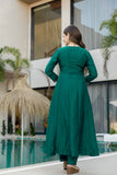 Woman in a green dress standing by a pool with a modern building in the background Glanzavi