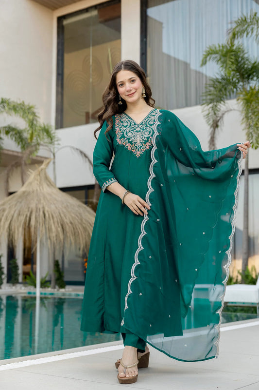 Woman in a teal traditional outfit with embroidery standing by a pool Glanzavi