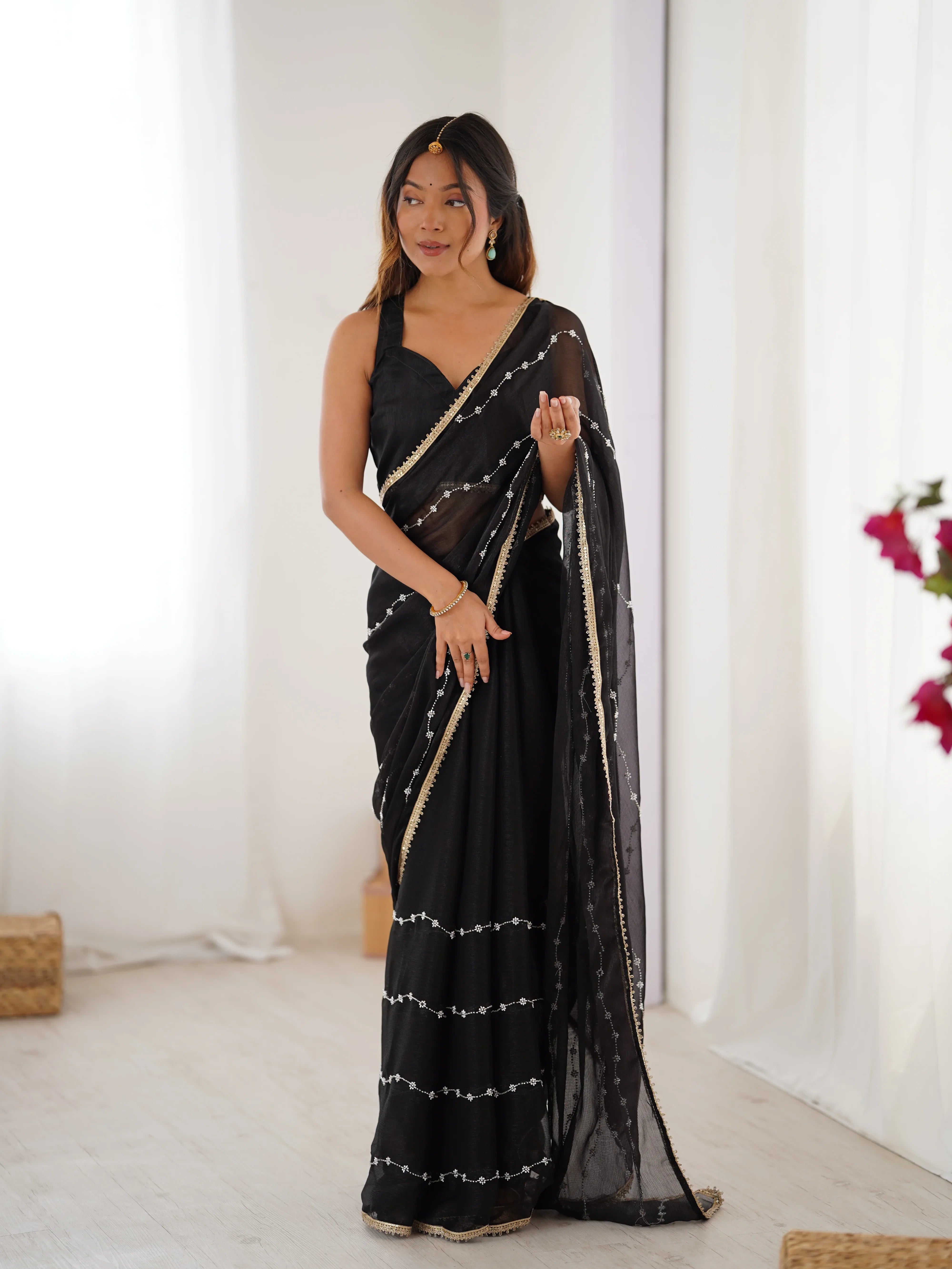 Woman wearing a black saree with white patterns in a minimalistic setting Glanzavi