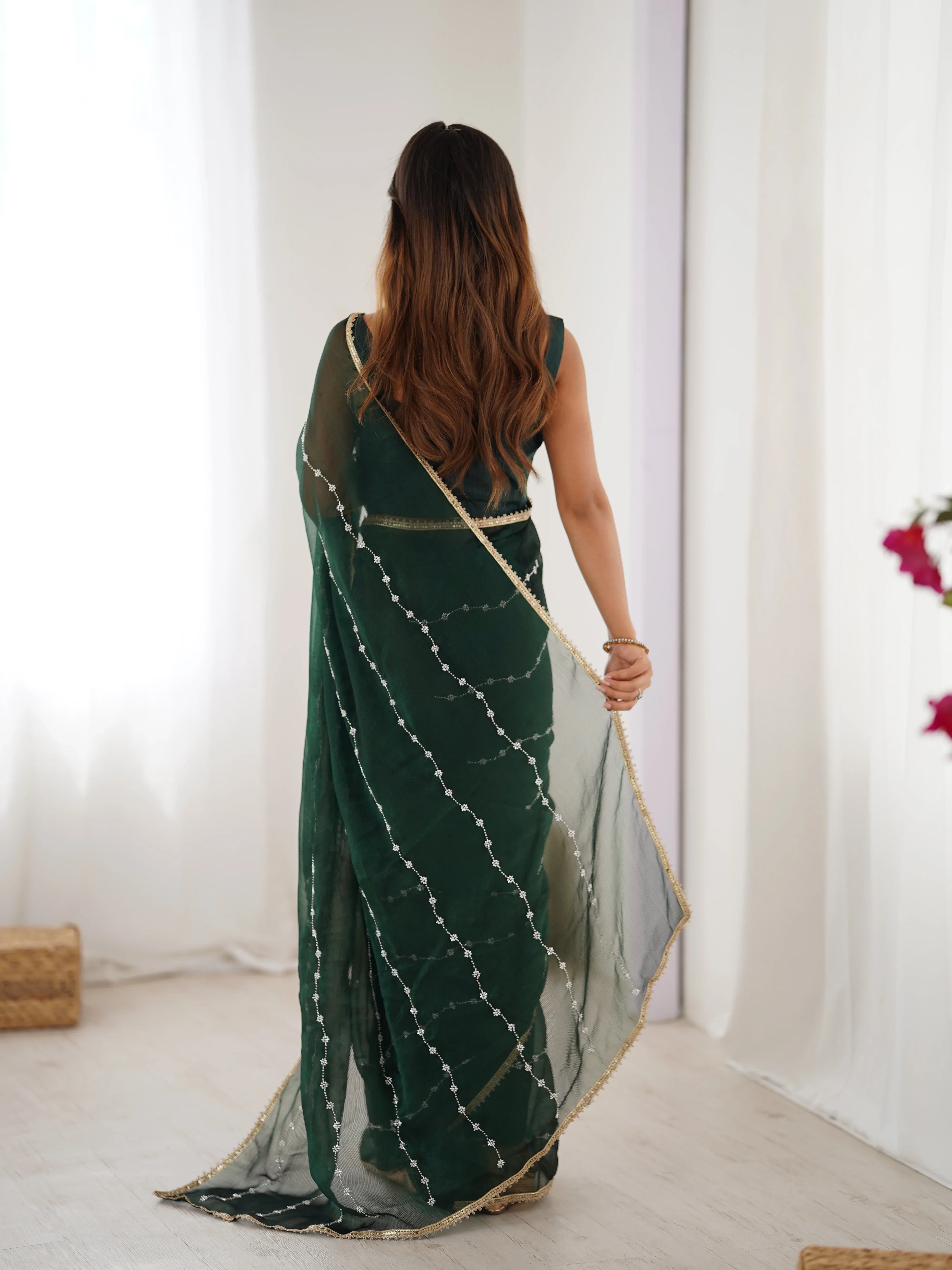 Woman wearing a green saree with a white border in a minimal indoor setting Glanzavi