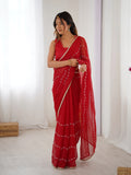 Woman wearing a red saree with white patterns in a minimal indoor setting Glanzavi