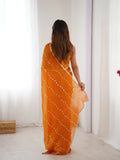 Woman wearing an orange saree with a white pattern in a minimal indoor setting Glanzavi