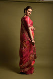 Woman wearing a pink saree with a gold border against a plain background Glanzavi