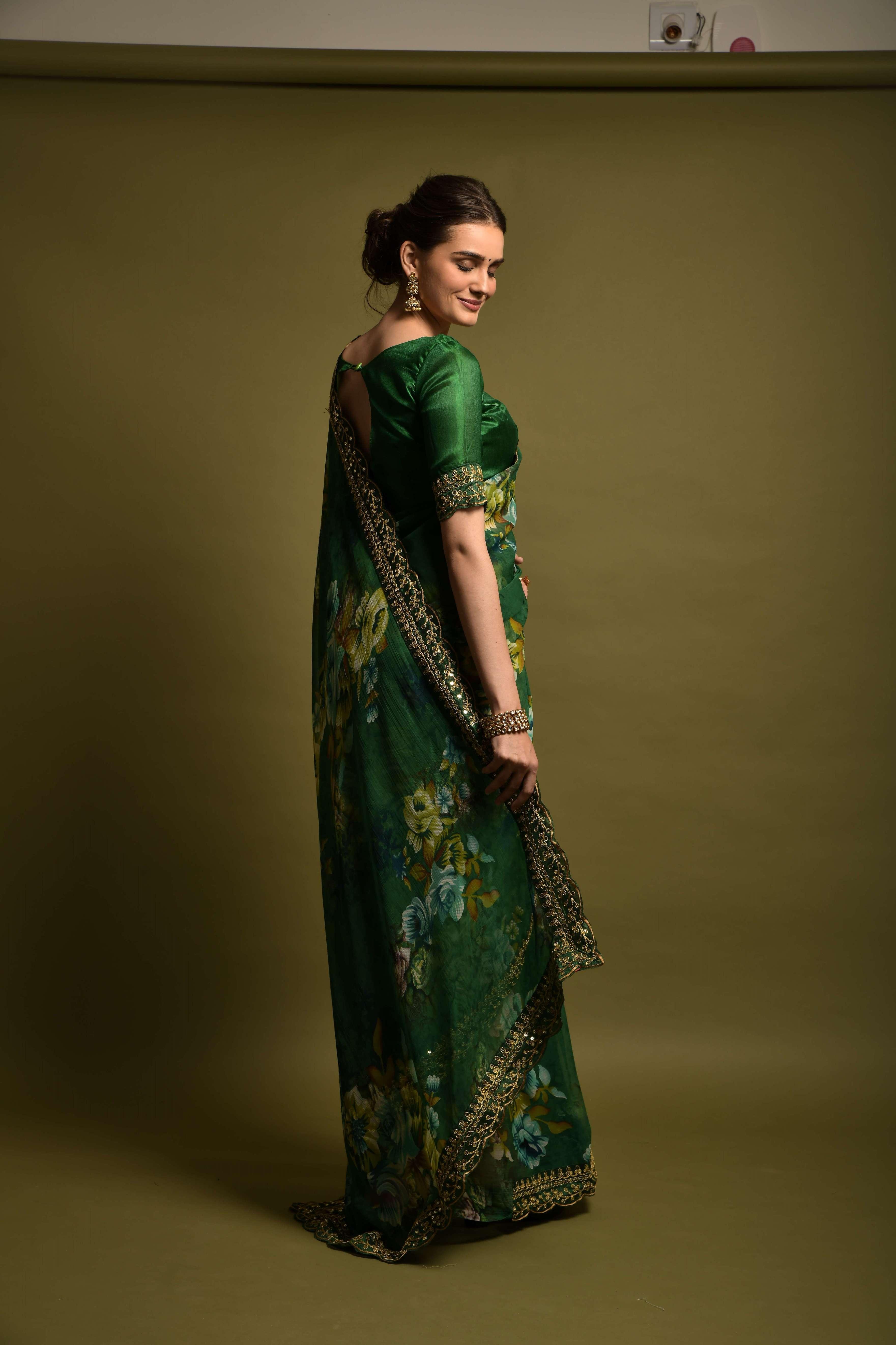 Woman wearing a green saree with floral patterns against a plain background Glanzavi